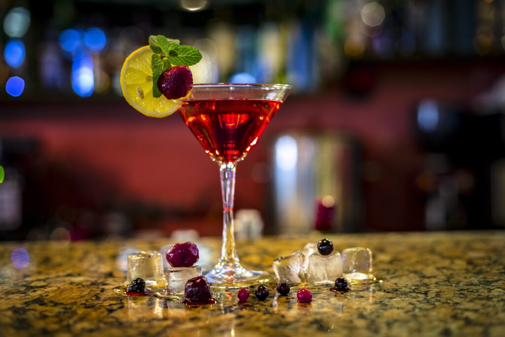 A glass of red liquid with fruit on it.