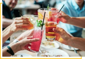 A group of people holding drinks at a table.