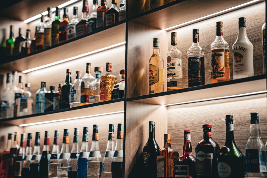 A wall of shelves with bottles and glasses on them.